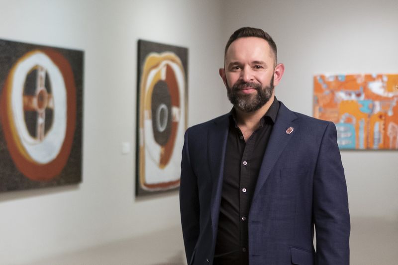 Portrait of a man standing in front of artworks in an Art Gallery