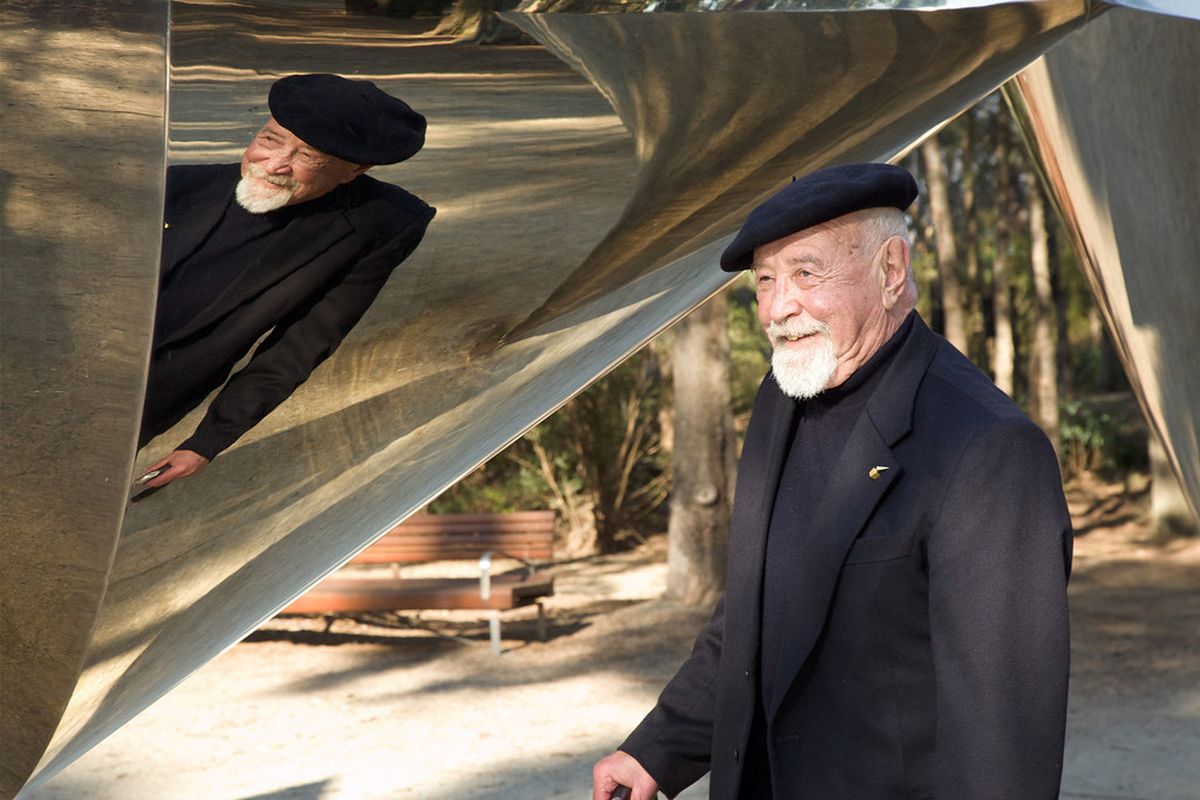 The artist Bert Flugelman standing in front of Cones - a large-scale sculpture of seven steel cones.