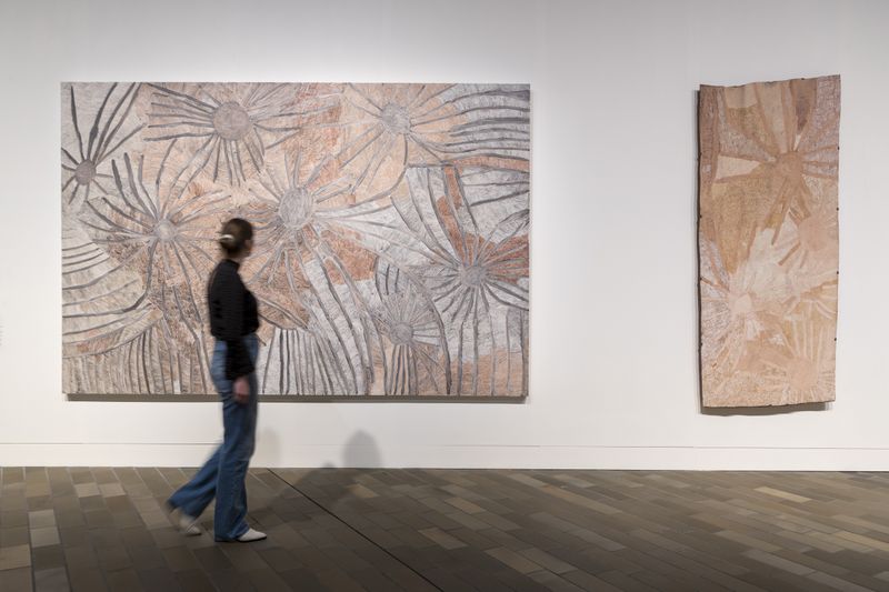 Woman in dark clothing walking in front of art in gallery space