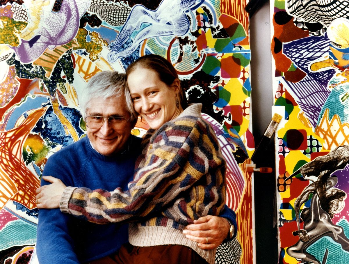 A couple embrace in front of a colourful artwork