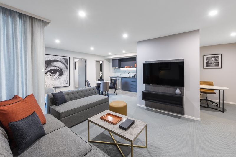 View of hotel room showing a couch, tv and kitchenette