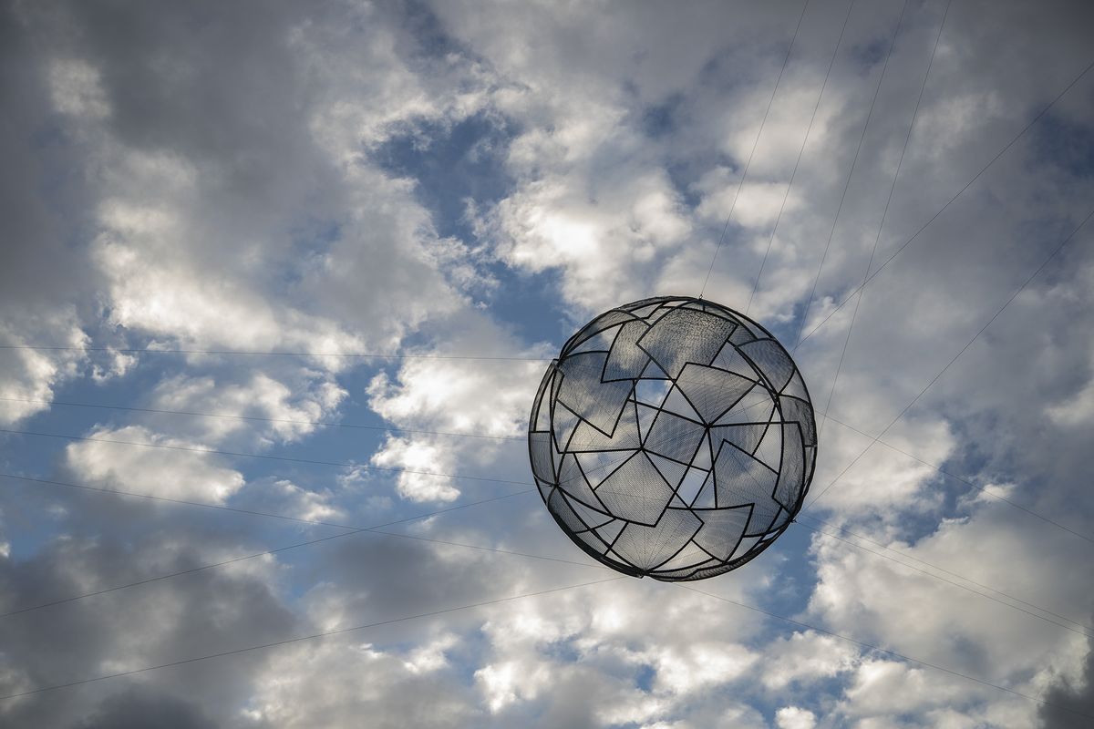 A sphere made of interlocking geometric shapes hangs in the sky
