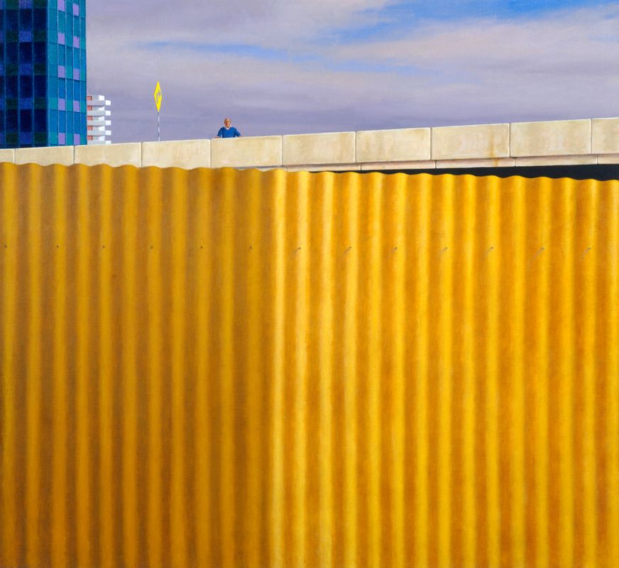 Painting of a large yellow corrugated iron fence in the foreground and man wearing a blue jumper standing bridge in the background