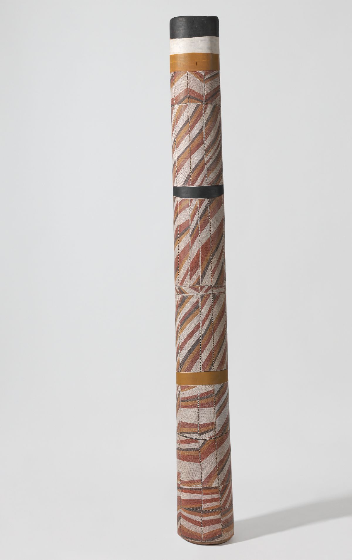 Tall ochre, yellow, white and black pole with repeating stripe patterns