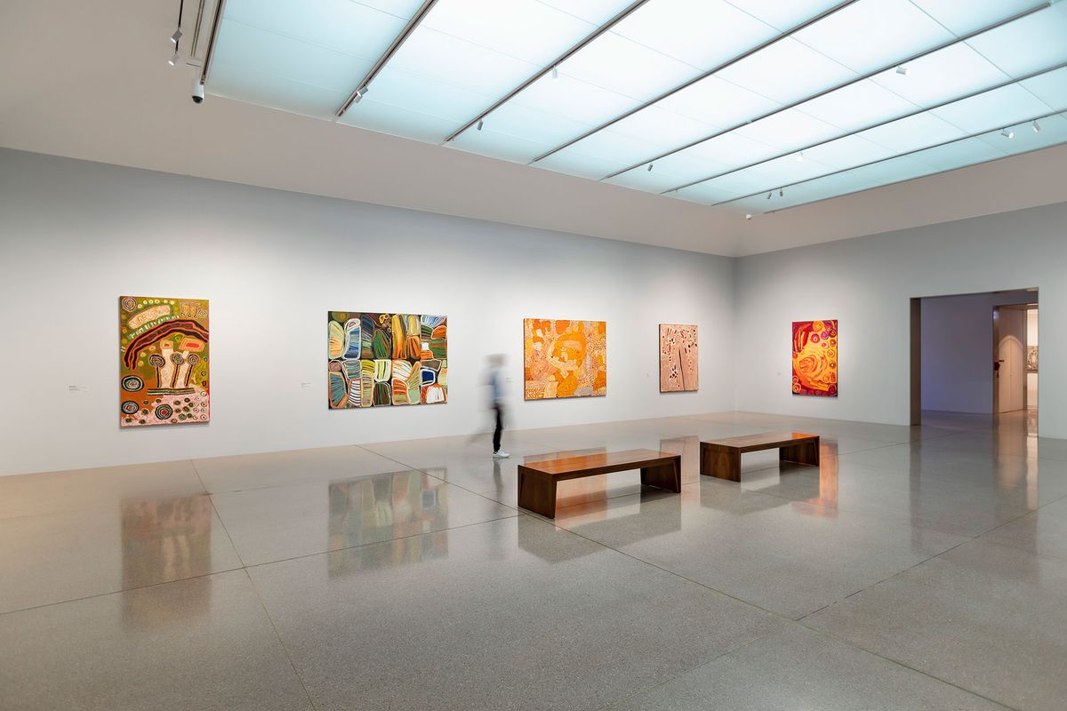 a person in blurred motion is walking through a gallery space