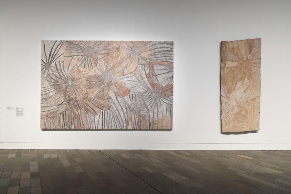 Two large paintings are hanging on a wall in a large gallery space.