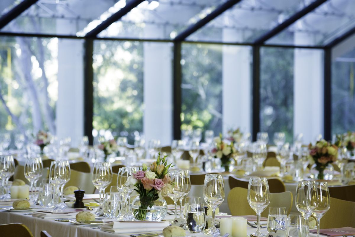 Tables are set for an event with flowers and place settings in a large room